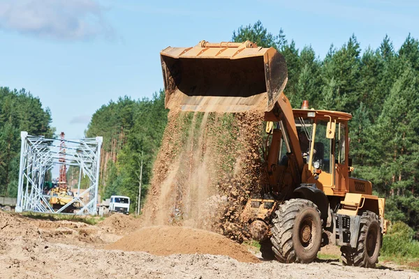 Radladermaschine entlädt Sand bei Umzugsarbeiten auf Baustelle — Stockfoto