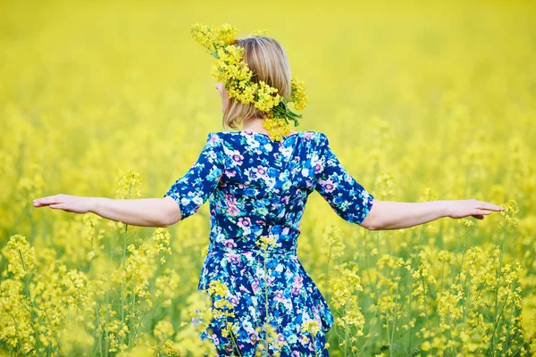Primavera. mujer con guirnalda de flores en el prado de semillas de colza amarilla — Foto de Stock