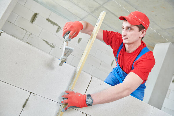 walling. bricklayer installing wall from autoclaved aerated concrete blocks