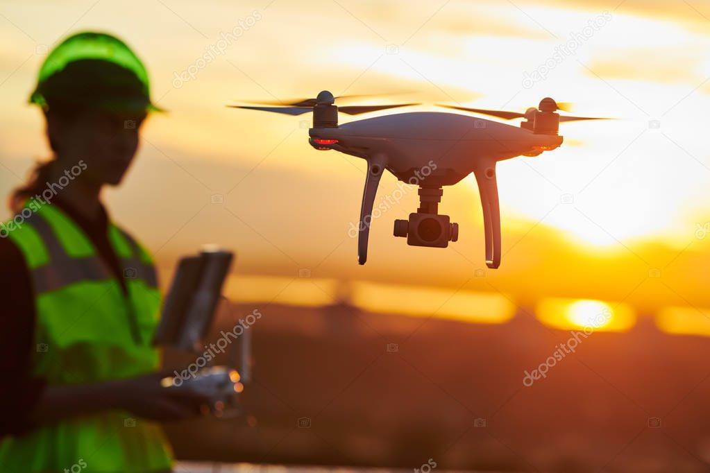 Drone inspection. Operator inspecting construction building site flying with drone. sunset