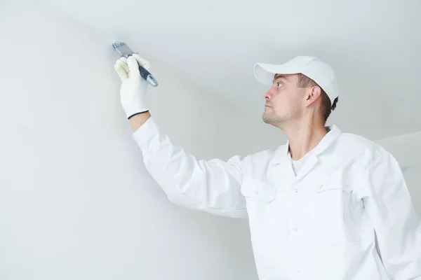 Malerei. Maler mit Pinsel, der den Deckenwinkel mit weißer Farbe bedeckt — Stockfoto