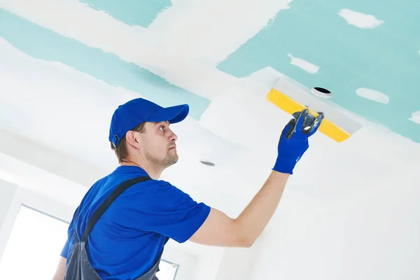 Refurbishment. Plasterer spackling a gypsum plasterboard ceiling with putty — Stock Photo, Image