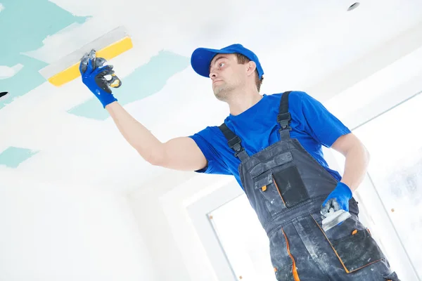 Remodelação. Estucador spackling um teto de gesso de gesso com massa de vidraceiro — Fotografia de Stock