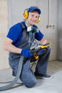 smiling worker at concrete floor surface grinding by angle grinder machine clipart