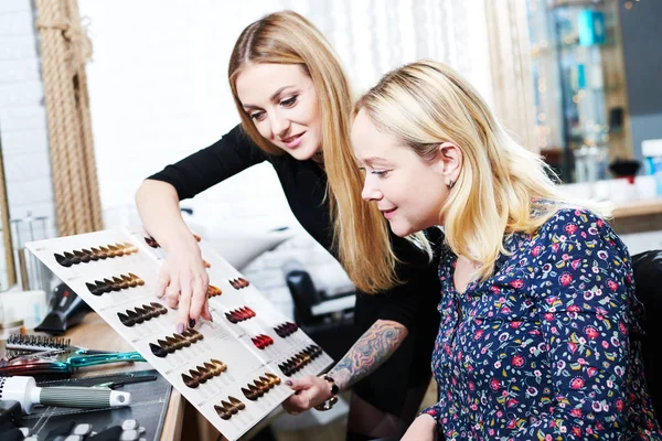 Stylist aiuta il cliente femminile a scegliere il colore della tintura per capelli con il grafico dei campioni di capelli — Foto Stock