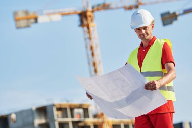 İnşaat alanında planı olan inşaat işçisi.