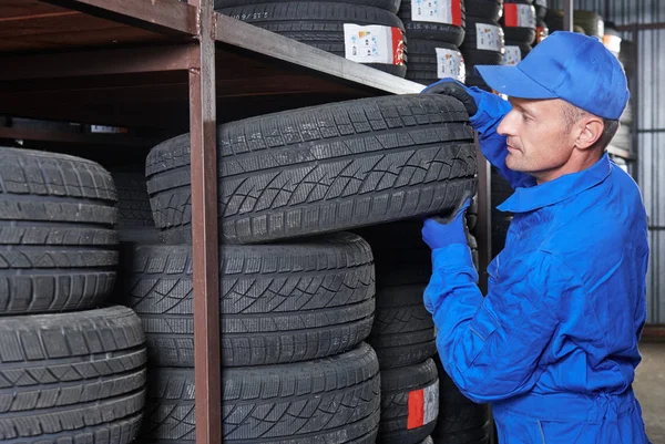 Mechanic pulls tire from the tyre store warehouse — Stock Photo, Image