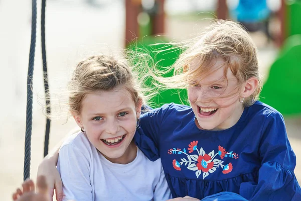 Freundschaft und Spaß in der Kindheit. zwei lachende junge Mädchen auf Schaukel — Stockfoto