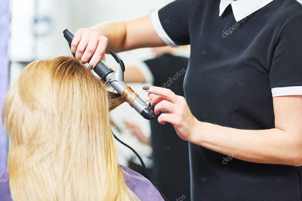 hairdo in beauty salon. hairdresser making coiffure with curl to wonam