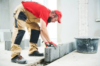 Tuğla döşeme işi ya da duvar örme. Sera beton bloklarla çalışan tuğla ustası.