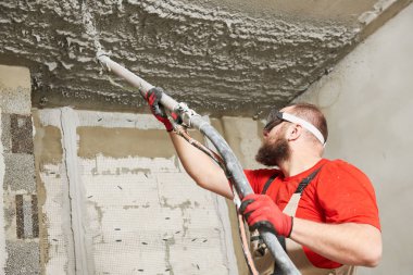 Plasterer spraying plastering mortar on ceiling with sprayer machine clipart