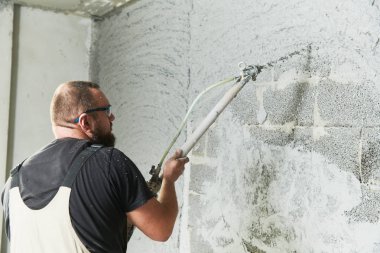 Plasterer using screeder spraying putty plaster mortar on wall clipart
