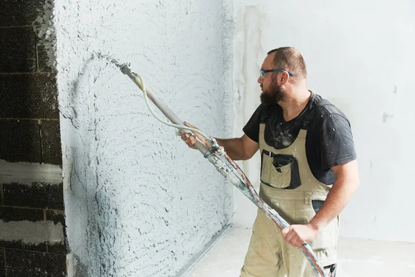 Plâtrier utilisant pulvérisation de mastic pulvérisation mortier de plâtre sur le mur — Photo