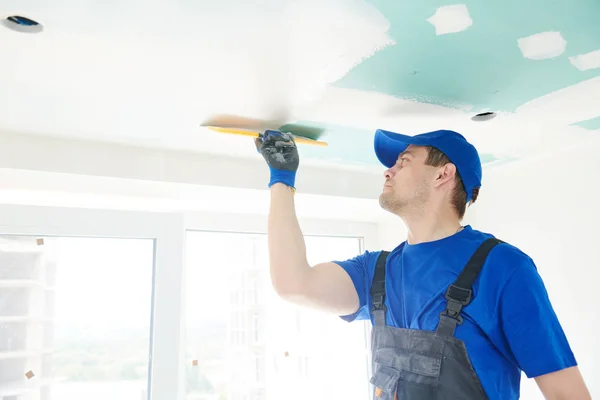 Rénovation. Plâtrier écartant un plafond de placoplâtre avec mastic — Photo