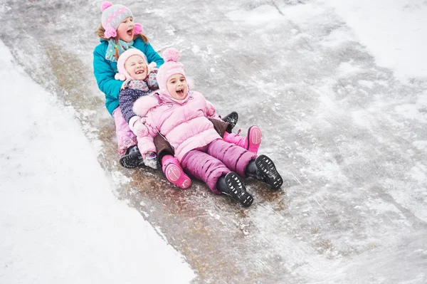 Kinderen plezier paardrijden ijs dia in de winter — Stockfoto