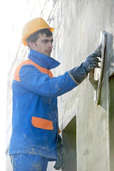 Constructor en el trabajo de enlucido de fachada con el cuchillo de masilla flotador —  Fotos de Stock