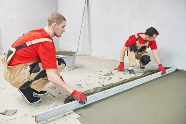 Bodenzementarbeiten. Gipser glättet Bodenfläche mit Estrich — Stockfoto