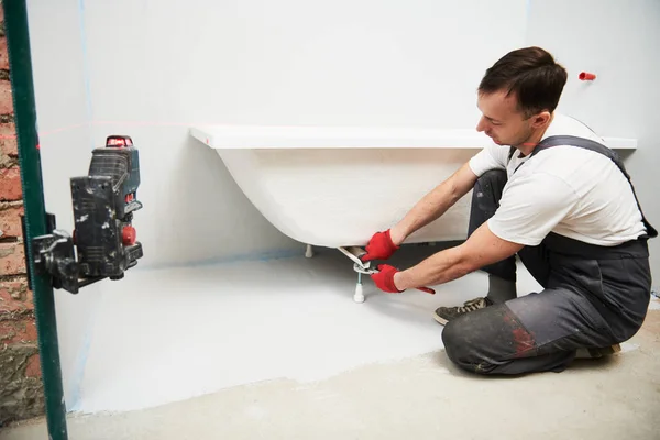 Pemasangan tabung mandi. tukang ledeng menginstal dan pemasangan kamar mandi dengan tingkat laser — Stok Foto
