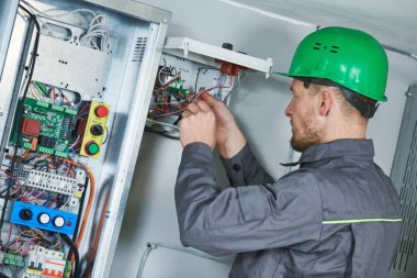 Electrician make maintenance in engine room of elevator clipart