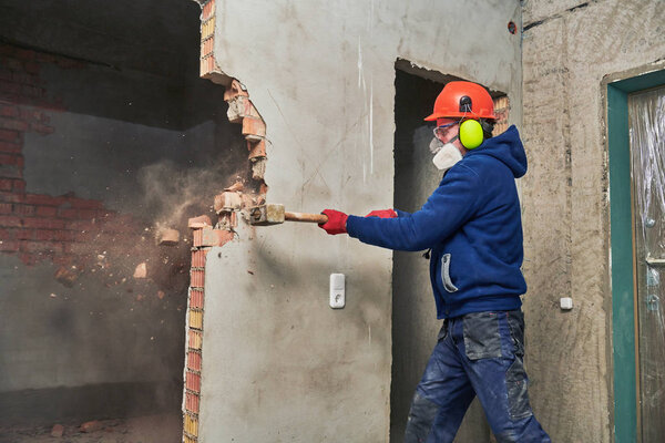 demolition work and rearrangement. worker with sledgehammer destroying wall