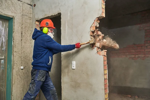 Trabalho de demolição e rearranjo. trabalhador com marreta destruindo parede — Fotografia de Stock