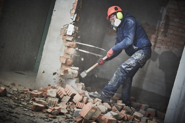 demolition work and rearrangement. worker with sledgehammer destroying wall