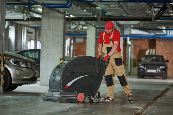 Pracownik z podłogą do czyszczenia maszyn w garażu. — Zdjęcie stockowe