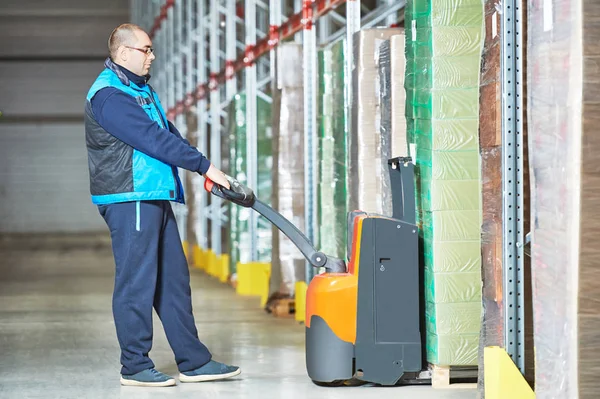 Trabajador con transpaleta apilando cajas de cartón —  Fotos de Stock