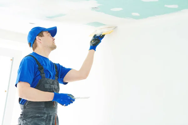 Sanierung. Gipser, der eine Gipskartondecke mit Spachtel auslegt — Stockfoto