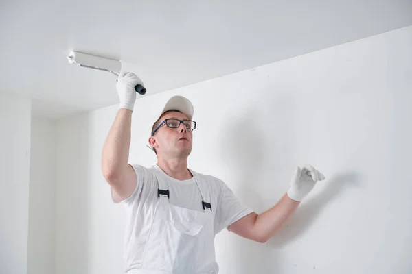 Peintre travailleur avec rouleau peinture surface de plafond en blanc — Photo
