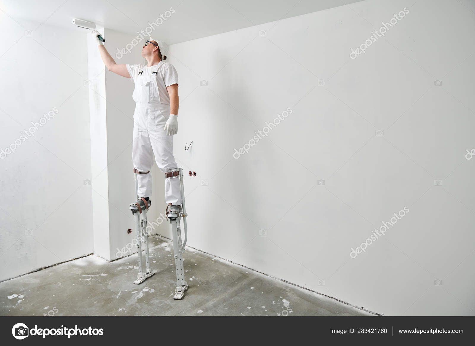 Painter Worker On Stilts With Roller Painting Ceiling Into