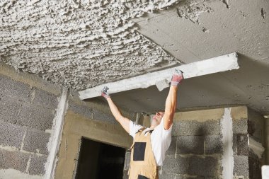 Plasterer smoothing plaster mortar on ceiling with screeder clipart