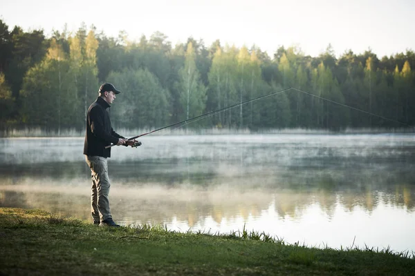 Pesca. pescatore con asta di filatura al mattino presto — Foto Stock