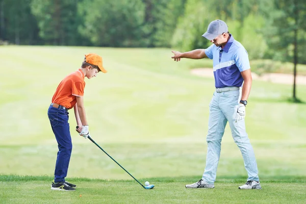 Мальчик играет в гольф летом с тренером — стоковое фото