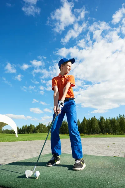 Мальчик играет в гольф на поле летом — стоковое фото