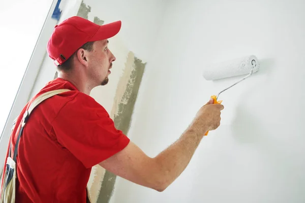 Trabalhador pintor com superfície de parede de pintura de rolo em branco — Fotografia de Stock
