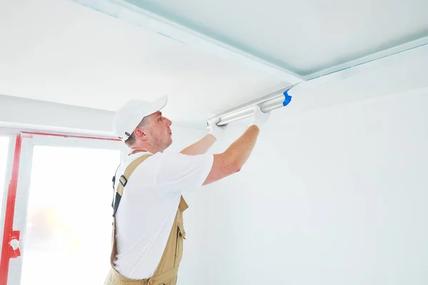 Pintor con cuchillo de masilla. Yesero alisar la superficie del techo en la renovación del hogar —  Fotos de Stock
