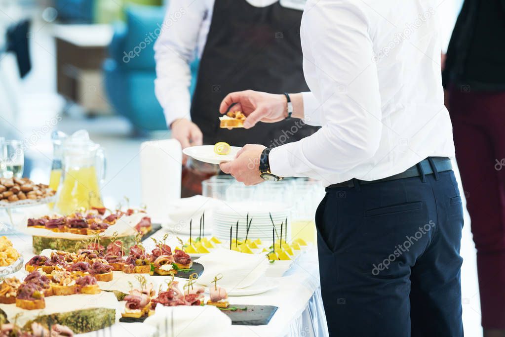 Catering service. man take snack from food court table at event