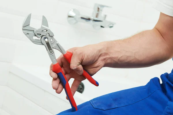 Serviço de canalizador. mão com chave na frente da torneira do banheiro — Fotografia de Stock