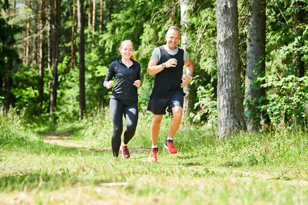 Man and woman jogging and running outdoors in forest — Stock Photo, Image