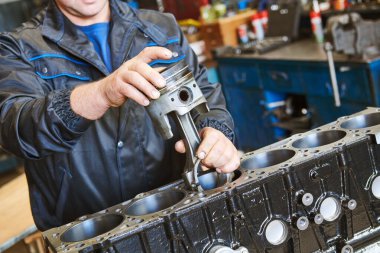 Dizel kamyon tamir servisi. Otomobil mekaniği motora piston yüklüyor