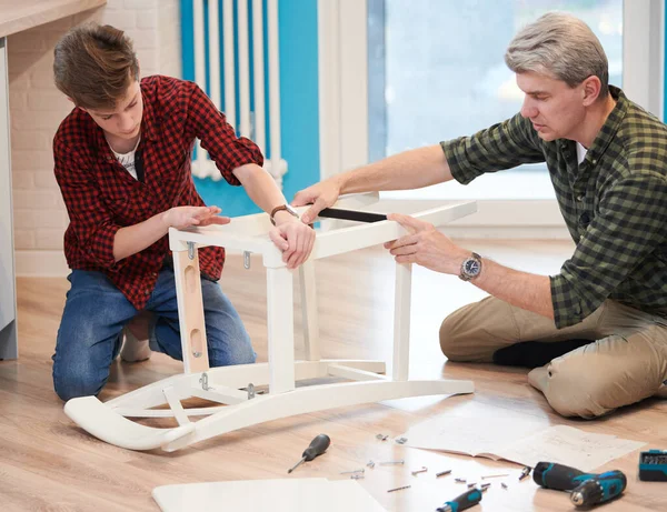 Vader en zoon werken samen. keukenstoel monteren — Stockfoto