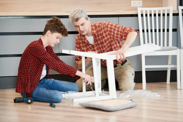 Ojciec i syn pracują razem. montaż krzesła kuchennego — Zdjęcie stockowe