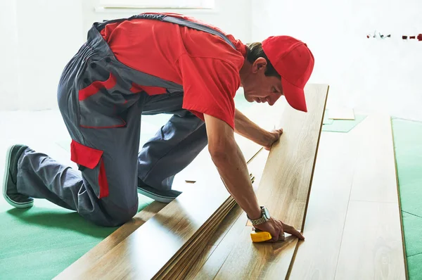 Trabalhador que estabelece piso laminado cobertura em casa renovação — Fotografia de Stock
