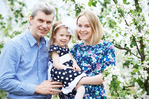 Smiling young adult family portrait in blossoming apple tree garden — Stock Photo, Image