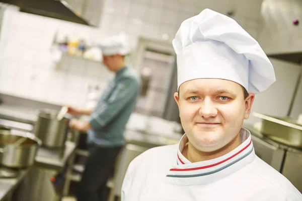 Portret van een lachende mannelijke chef-kok in de keuken staan — Stockfoto