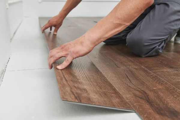 Munkás csatlakozik vinil padlóburkolat otthon felújítás — Stock Fotó