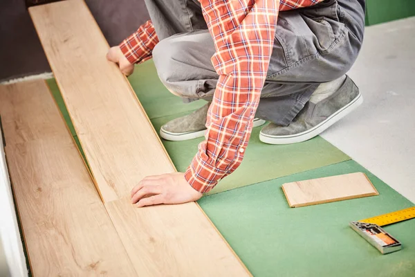 Werknemer die laminaatvloerbedekking bij de renovatie thuis legt — Stockfoto