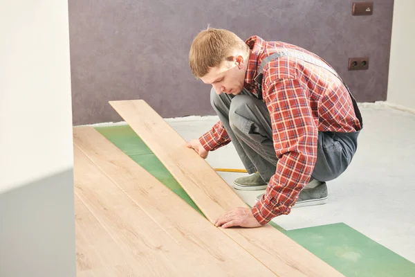 Werknemer die laminaatvloerbedekking bij de renovatie thuis legt — Stockfoto