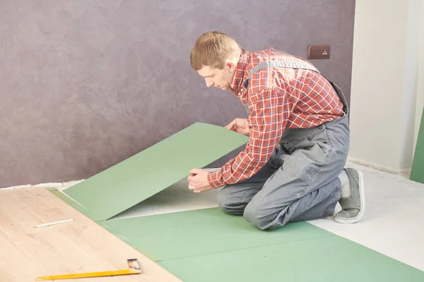 Trabalhador que estabelece piso laminado cobertura em casa renovação — Fotografia de Stock